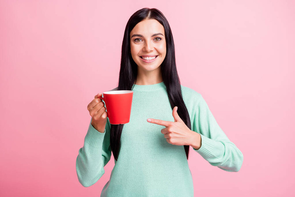 Photo portrait of girl pointing finger at red cup in one hand isolated on pastel pink colored background - Zdjęcie, obraz