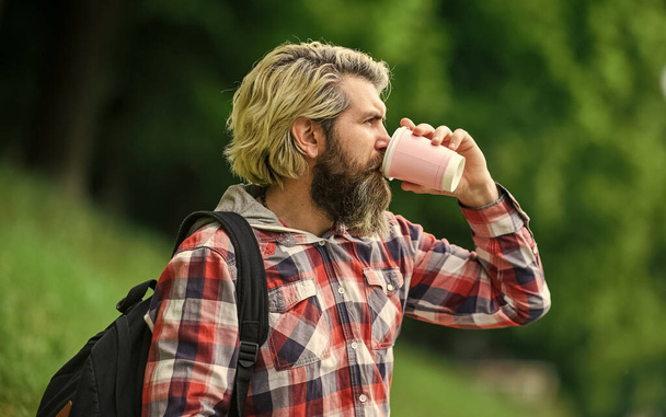 Drinking hot coffee. Enjoying nature at riverside. Guy with backpack relaxing. Inspiration. Inspired handsome hipster. Drink tea or coffee. Man with cup outdoors. Man outdoors with cup of coffee - Φωτογραφία, εικόνα