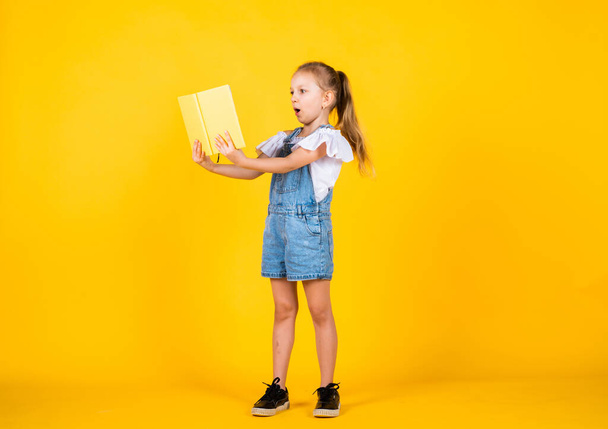 Dedicated to studying. notebook for making notes. childrens literature. back to school. happy childhood. cute child on yellow background. education. beautiful teen girl with books. kid like reading - Foto, afbeelding