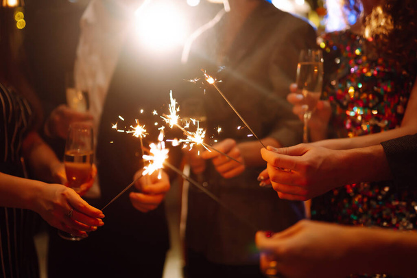 Glowing sparkles in hands. Group of happy people enjoying party with fireworks. Winter holiday, youth, lifestyle concept. - Fotoğraf, Görsel