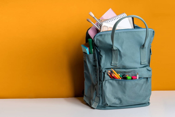 Blue backpack with different colorful stationery on a yellow background. Banner design - Foto, Imagem