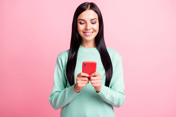 Photo portrait of woman holding phone with two hands typing isolated on pastel pink colored background - Φωτογραφία, εικόνα