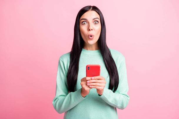Photo portrait of shocked woman holding phone with two hands isolated on pastel pink colored background - Fotografie, Obrázek