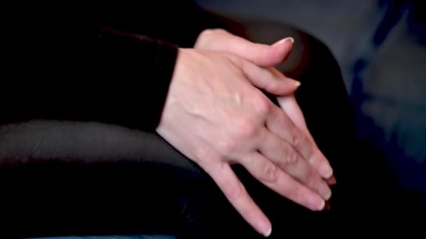 A nő a kezével dörzsöli a térdét. Egy nő ül a kanapén térdfájással.. - Felvétel, videó