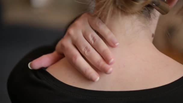 Eine Frau sitzt mit Schmerzen im Nacken auf der Couch. Die Frau reibt sich den Hals. - Filmmaterial, Video
