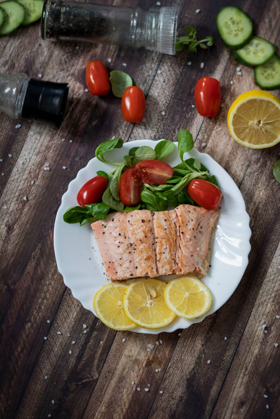 Salmon in a pan with lemon and other vegetables. Salmon on plates - Φωτογραφία, εικόνα