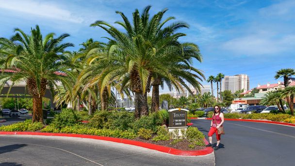 Las Vegas NV, USA 26-09-18 Approfittando della vista posteriore della città e delle palme colorate, una bella signora posa nella strada che circonda la parte anteriore del lussuoso Hotel Toscana - Foto, immagini