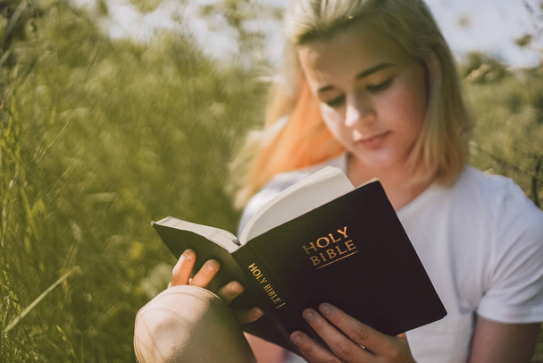 Genç Hıristiyan kız sahada İncil okuyor. İnanç, maneviyat ve din kavramı - Fotoğraf, Görsel