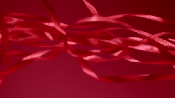 Rode zijde glanzende linten vallen neer op een matte achtergrond. 4k kwaliteit verticale opname beelden. - Video