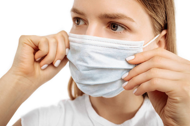 Young woman using medical protective mask to protect health and prevent influenza virus, epidemic and infectious diseases, on white background - Foto, afbeelding