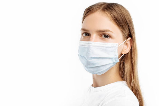Studio portrait of young woman in mask looking at camera, on isolated white background. Flu epidemic, coronavirus, virus protection - Fotografie, Obrázek