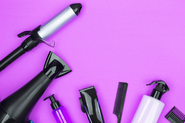Hairdressing tools in black: hair dryer, combs, sprays, curling iron, hair clipper on a lilac background, space for text, flat lay. - Fotó, kép