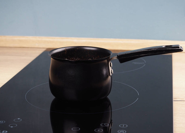 Kaffee wird in Cezve auf einem modernen Induktionsherd gebrüht. - Foto, Bild