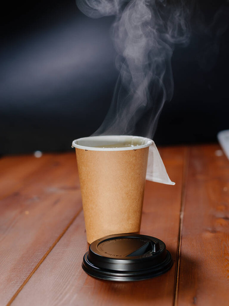 Hot tea in craft paper cup without logo. Steam rises above the paper cup of tea. - Fotografie, Obrázek