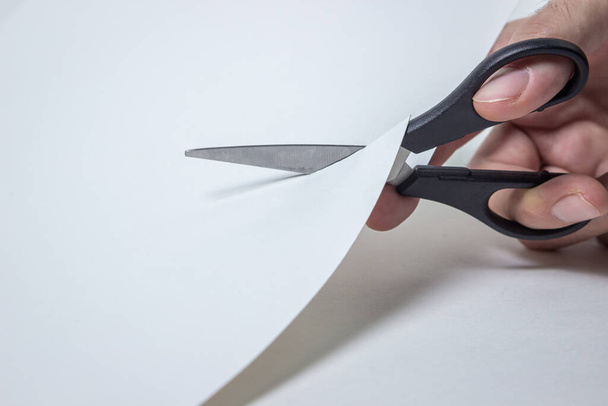 Scissors cut through the white paper. Working with paper. - Fotoğraf, Görsel