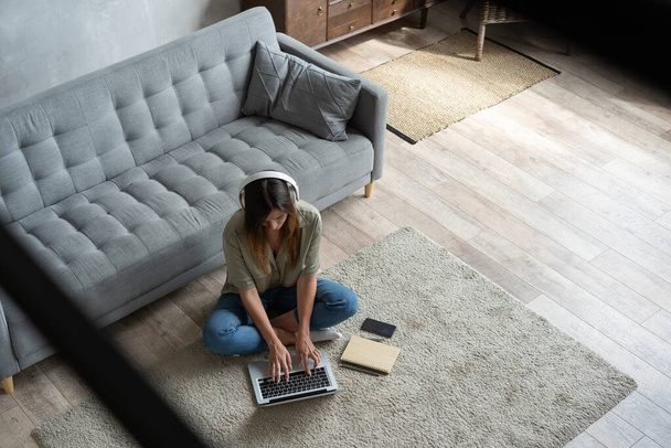 Just inspired. Confident young beautiful smiling woman working on laptop while sitting on the floor at home. - Foto, Imagem