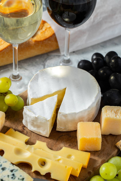 Ochutnávka sýrové mísy na dřevěném talíři. Jídlo pro víno a romantické rande, sýrové pochoutky na lehkém betonovém pozadí - Fotografie, Obrázek