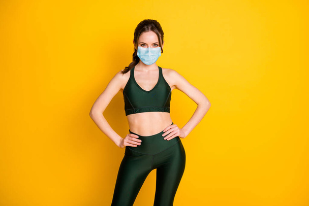 Portrait of nice cheerful slender sportive girl pilates instructor hands on hips wear mask isolated over bright yellow color background - Foto, Imagem