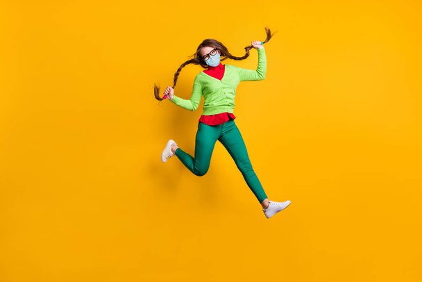 Full length body size view of funky cheerful girl jumping running holding pigtails wear mask isolated bright yellow color background - Foto, Imagen