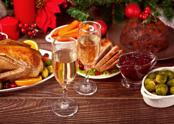 Table served for thanksgiving or Christmas dinner. Two glasses of wine or champagne. Stuffed roasted turkey, pudding and ham. Traditional celebrating holiday. Top view. - Foto, afbeelding