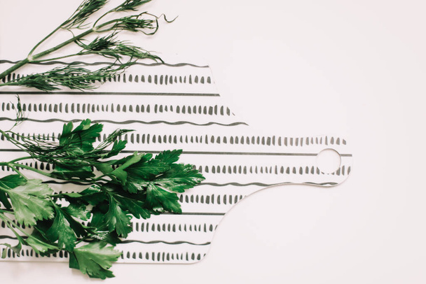 Greenery, fresh parsley on cutting board  on white background. Preparing fresh healthy vegetarian meal. Top view, flat lay - Фото, зображення