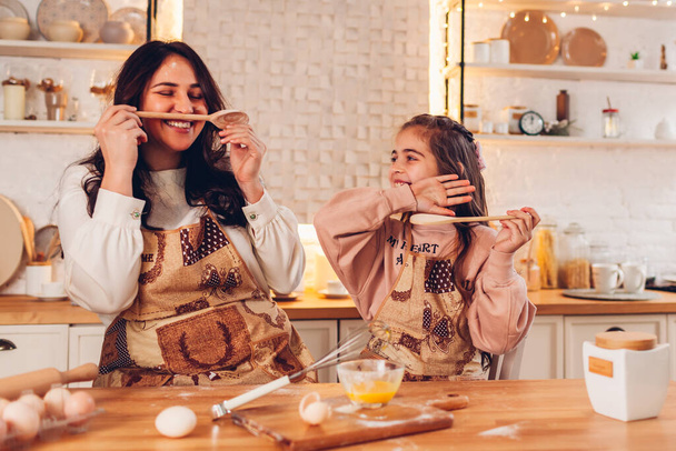 Family having fun with kitchen appliances cooking food for Christmas at home. Mother and little daughter laughing - Foto, Imagen