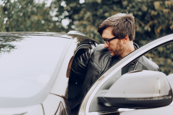 Stylish man in glasses sits in a car - 写真・画像