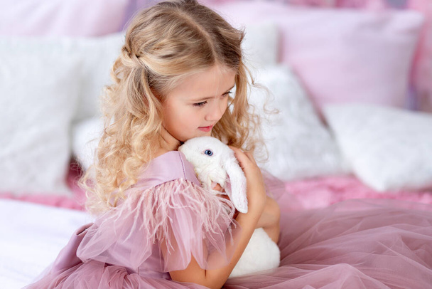Маленька дівчинка з кроликом на ялинці в красивій рожевій сукні, новий рік і Різдво концепції - Фото, зображення