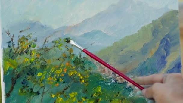 Hand van onbekende persoon die berglandschap en bomen schildert - Video