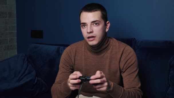 Een man geeuwt tijdens het spelen van een video games joystick controller op de bank thuis, in slow motion. - Video