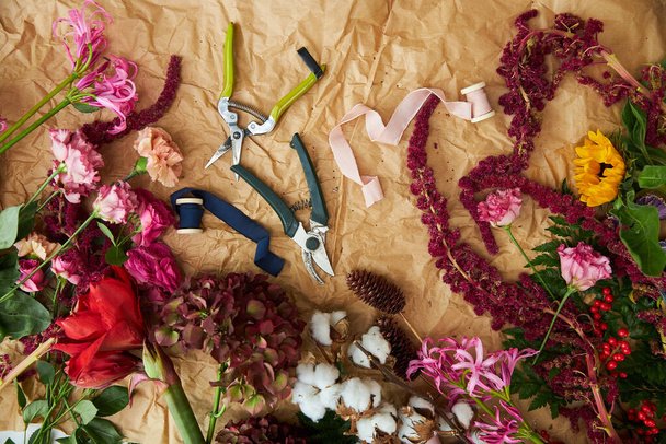 Composition flat-lay of flowers and florists instruments on parchment paper craft - Fotografie, Obrázek