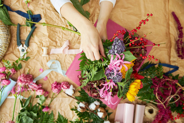 Flat lay composition florist creates a bouquet on craft paper and pink background paper - 写真・画像