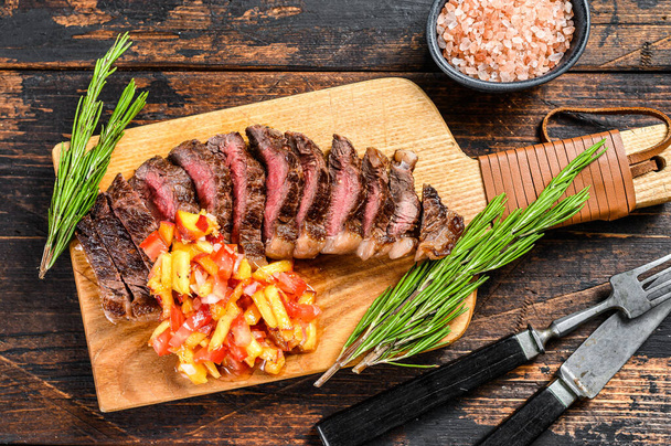 Grilled top sirloin cap or picanha steak on a cutting board with herbs. Dark wooden background. Top view. - Photo, Image