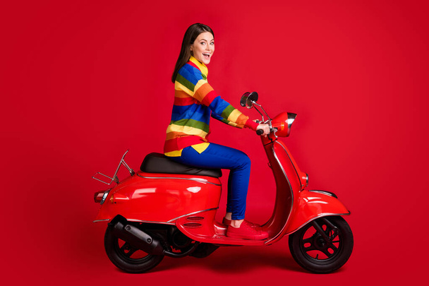Profile side view of pretty cheerful girl driving moped fast speed having fun isolated over bright red color background - Foto, Imagem