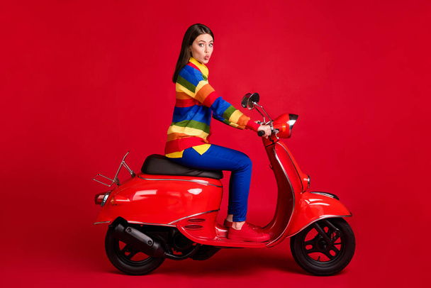 Profile side view of pretty funky flirty girl driving moped having fun pout lips isolated over bright red color background - Fotó, kép