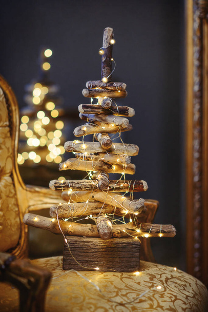 Driftwood Christmas tree with lights sitting on a chair - 写真・画像