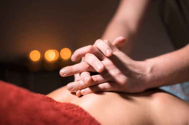 Male masseur doing back massage to client woman in dark room of massage spa - Фото, зображення