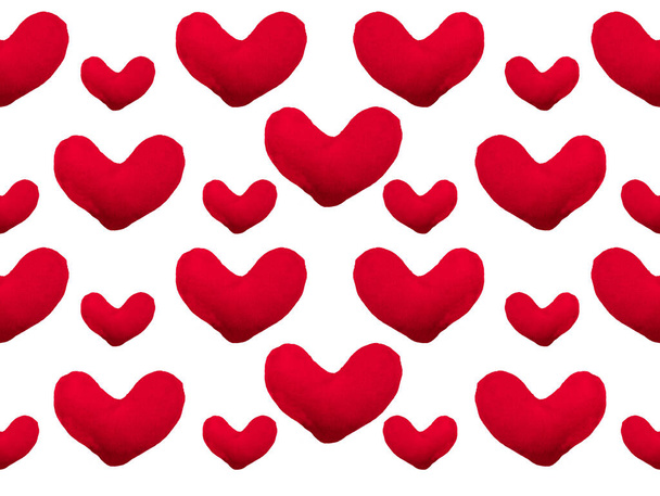 白い背景にバレンタインデーの心のパターン。心臓分離。ハンドメイドのフリース生地で作られた柔らかい赤いハート. - 写真・画像