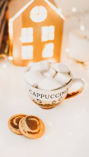 Coffee cup with marshmallows and cookies on bokeh lights background. Christmas and New Year cozy still life lights and decorations - Foto, immagini