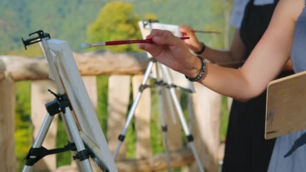 Mani di pittori che disegnano quadri su cavalletti all'aperto - Filmati, video