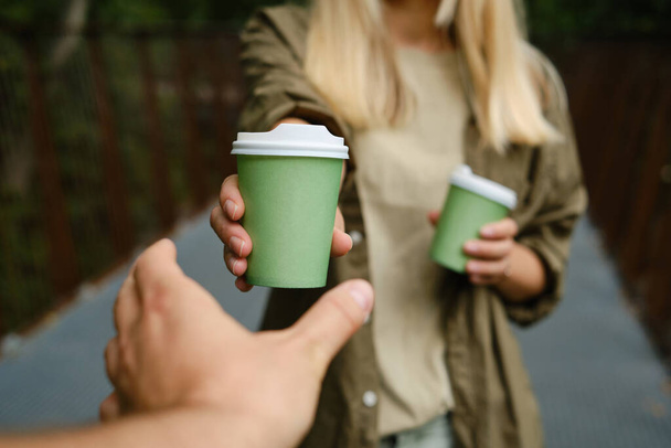 Green paper cup with coffee in woman hand. Time for drink coffee in city. Coffee to go. Enjoy moment, take a break. Disposable paper cup closeup. Delicious hot beverage. Blank space for text, mockup - Foto, immagini