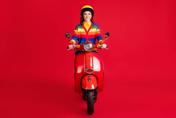 Photo portrait of smiling woman riding retro scooter forward isolated on vivid red colored background - Foto, immagini