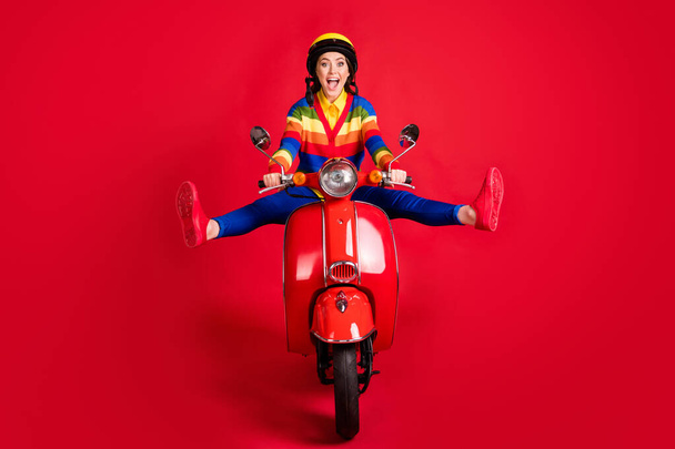 Photo portrait of excited woman spreading legs like star riding scooter isolated on vivid red colored background - Zdjęcie, obraz