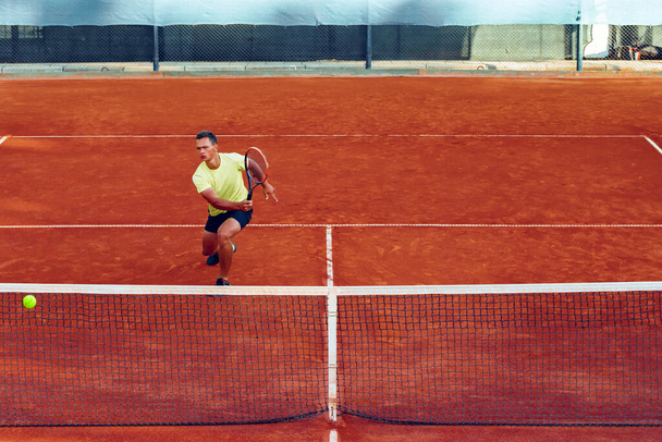 Mladý pohledný muž hraje tenis na tenisovém kurtu - Fotografie, Obrázek