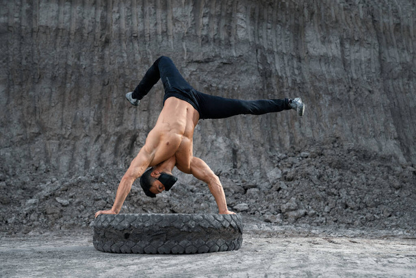 Fitness man with bare torso doing handstand outdoors - Foto, Bild