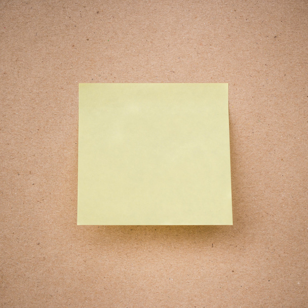 kahverengi kağıt dokusu üzerinde sarı yapışkan not yakın çekim - Fotoğraf, Görsel