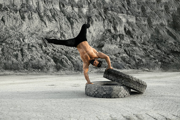 Sporty man in face mask doing push ups on tyres - Фото, изображение