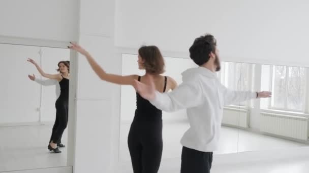 Mladý krásný pár studující taneční sál. Profesionální taneční pár tančí ve velkém, světlém, bílém sále - Záběry, video