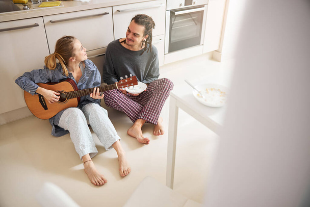 Hermosa mujer con guitarra pasar tiempo con el novio en casa - Foto, imagen