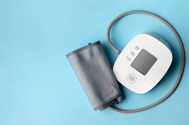 Monitor automático de presión arterial sobre fondo azul. tonómetro electrónico médico con espacio de copia - Foto, Imagen